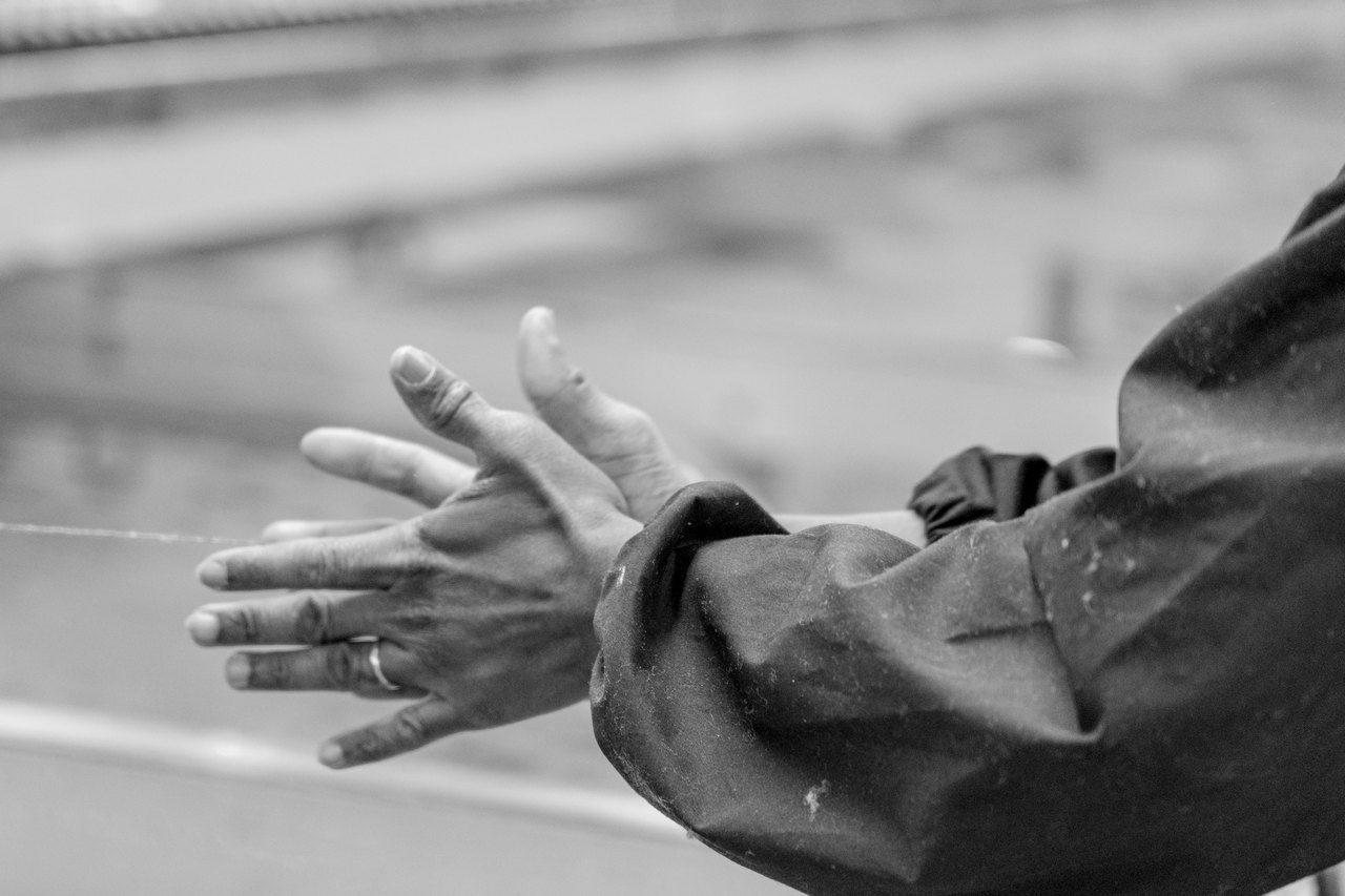 Le mani di un operaio, con la manica da lavoro coperta di fibra