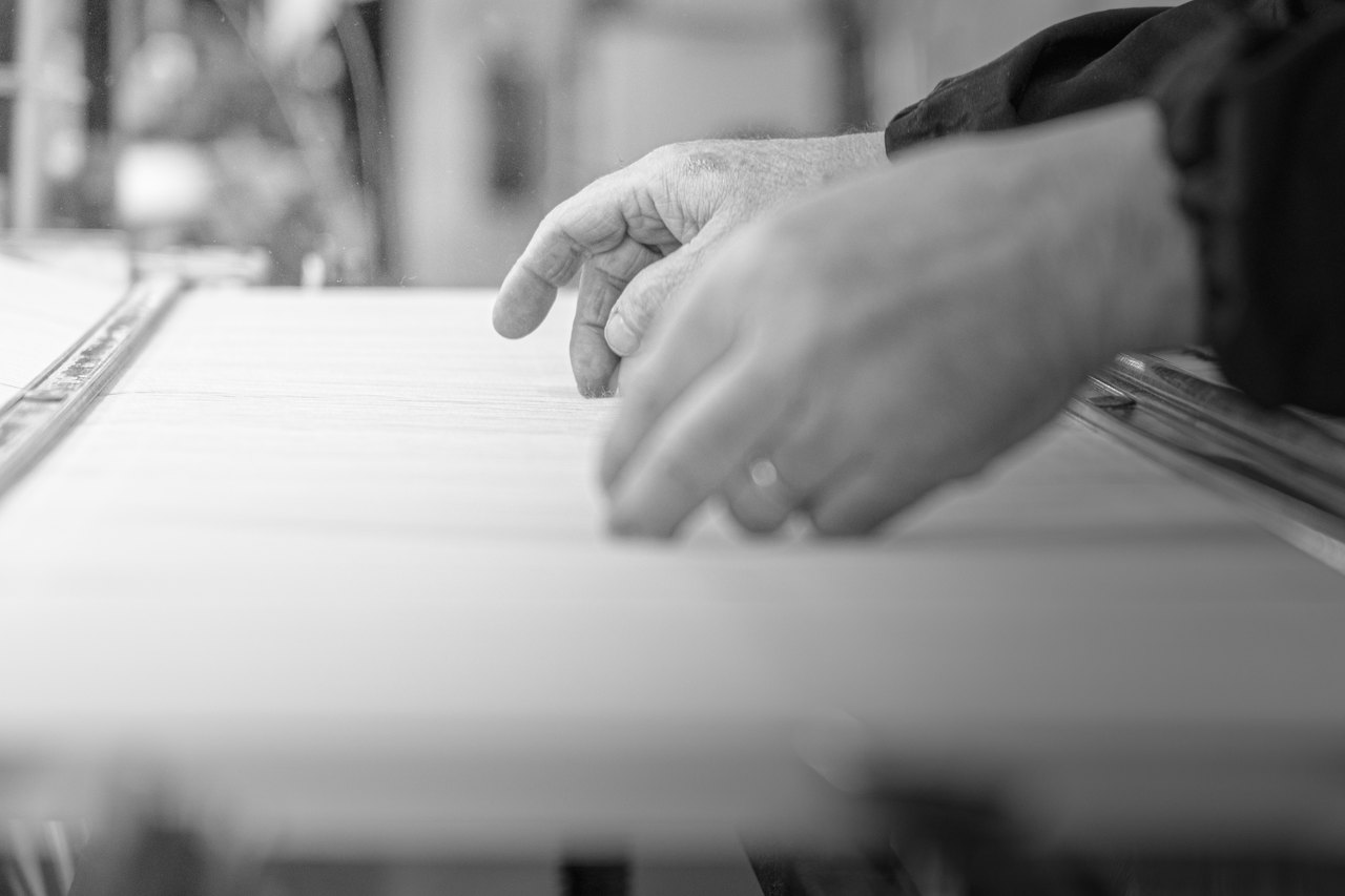 Le mani sui fili chiari di un telaio