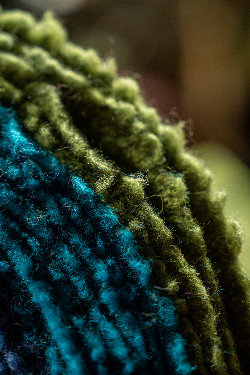 Macro di due tessuti ricci, verde e turchese, con le fibre in controluce