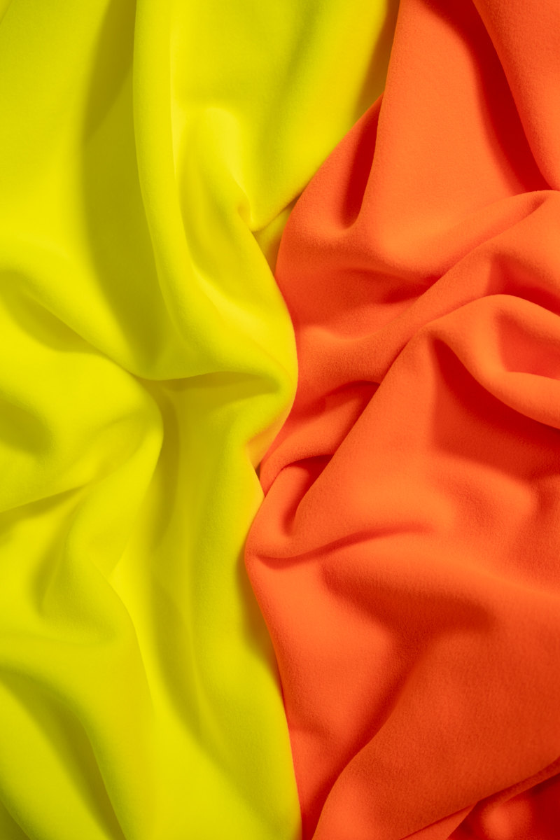 Due tessuti tecnici fluo, giallo e arancio, stesi in pieghe