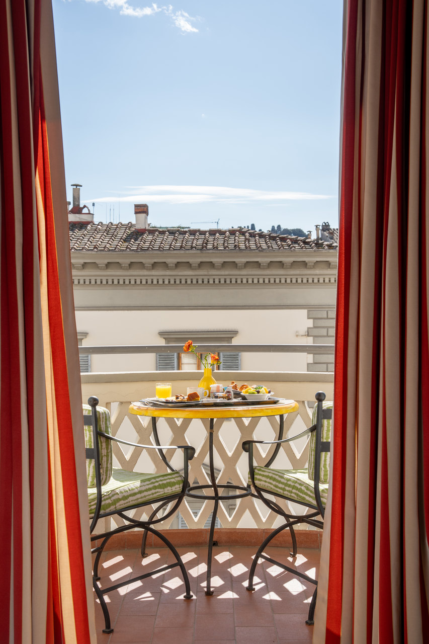 La porta finestra di una camera aperta sul balcone, col tavolino apparecchiato per la colazione