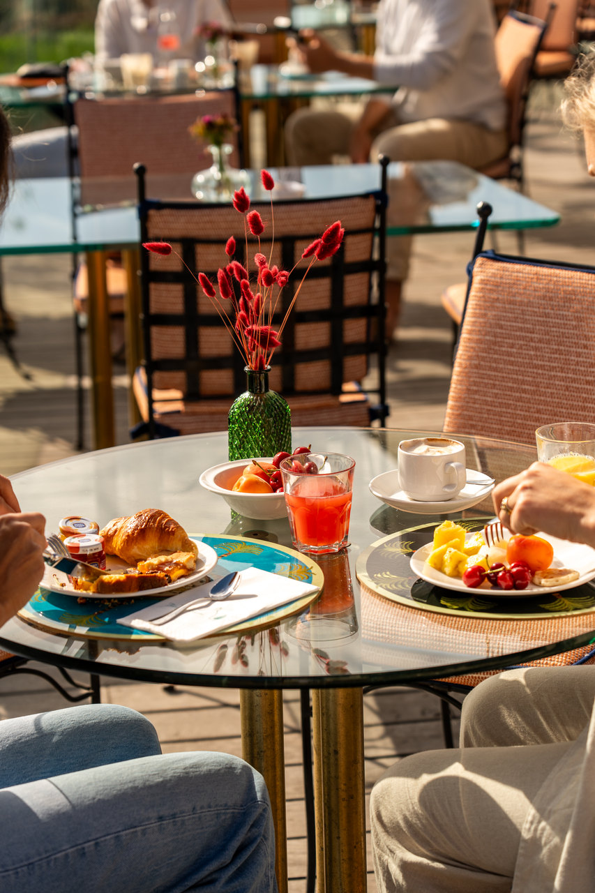 La colazione in terrazza: cornetti, frutta e caffè sul tavolo di vetro