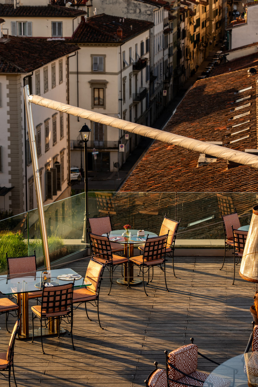 La terrazza del ristorante all'ultimo piano, coi tavoli pronti e i tetti intorno