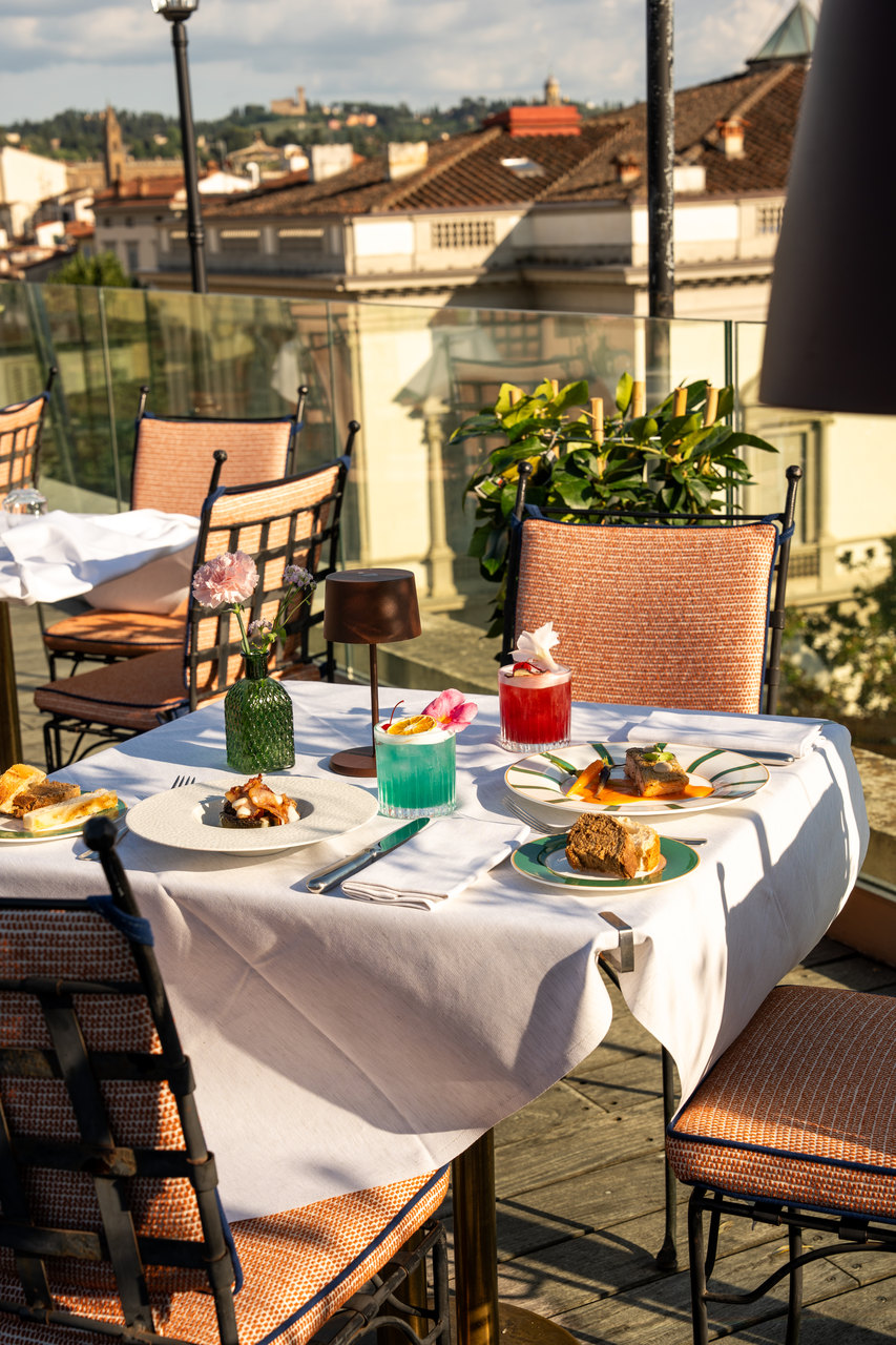 Un tavolo apparecchiato sulla terrazza, coi piatti e i bicchieri colorati