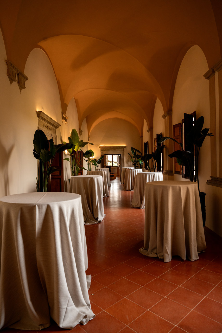 La galleria allestita coi tavoli alti e le tovaglie lunghe, sotto le volte