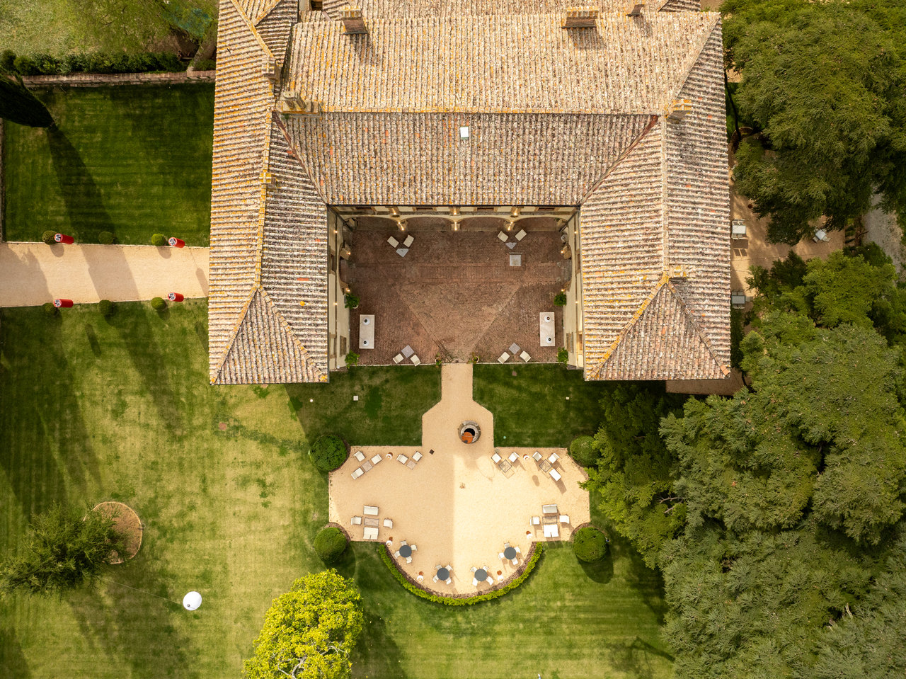 La villa a picco dal drone: il tetto e la pianta a ferro di cavallo attorno al cortile, la terrazza a semicerchio e il prato